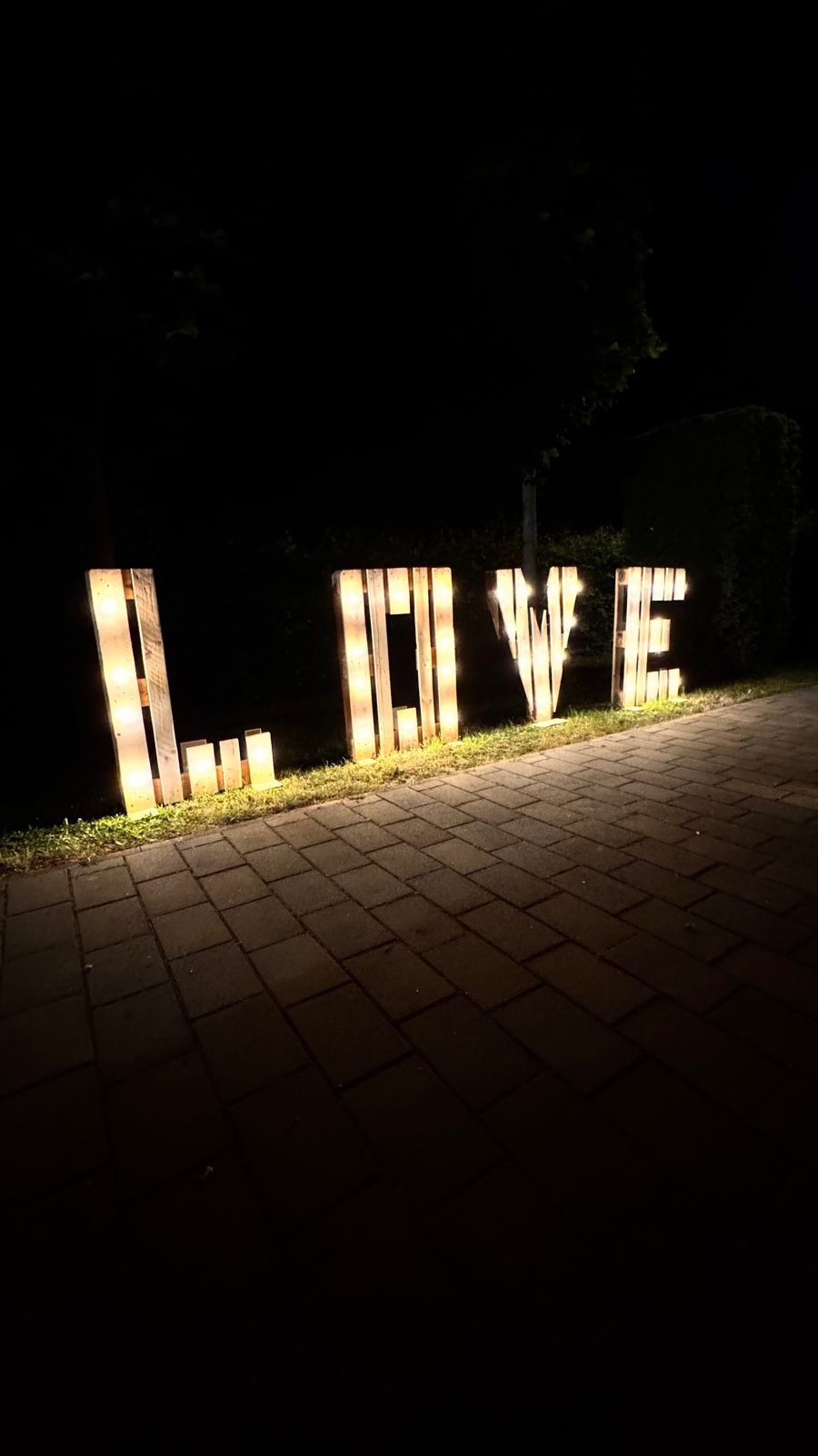 Leuchtende LOVE-Buchstaben aus Paletten bei Nacht